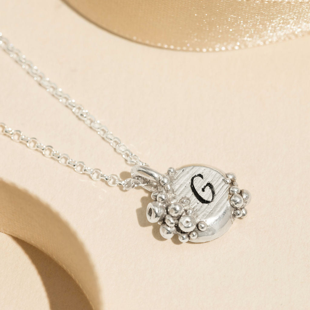 Personalised sterling silver barnacle pendant necklace with hand-stamped initial G, featuring organic ocean-inspired texture and bold silver detailing