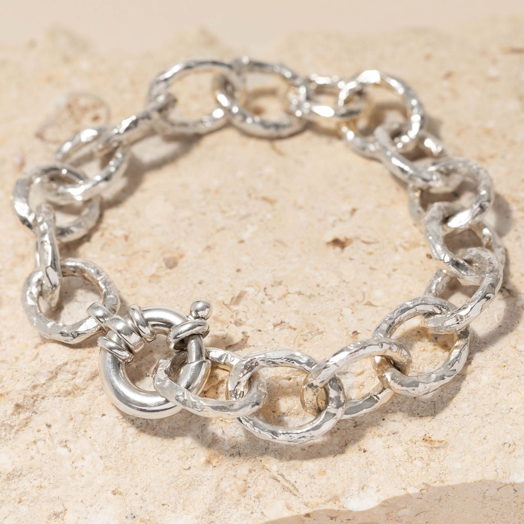 Chunky sterling silver bracelet with hand-carved sandbank texture and bold clasp, displayed on natural stone surface by Rockpool Jewellery