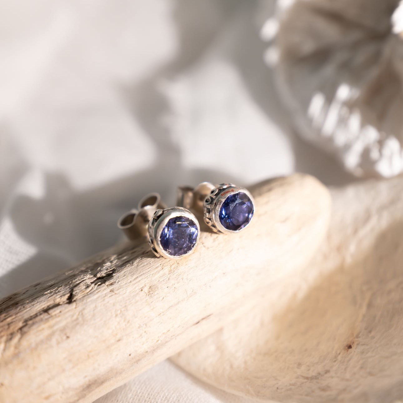 Blue gemstone earrings on a piece of wood with white background