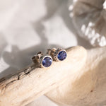 Blue gemstone earrings on a piece of wood with white background