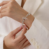 T bar bracelet with granulated clasp shown on models wrist, model wearing white jacket