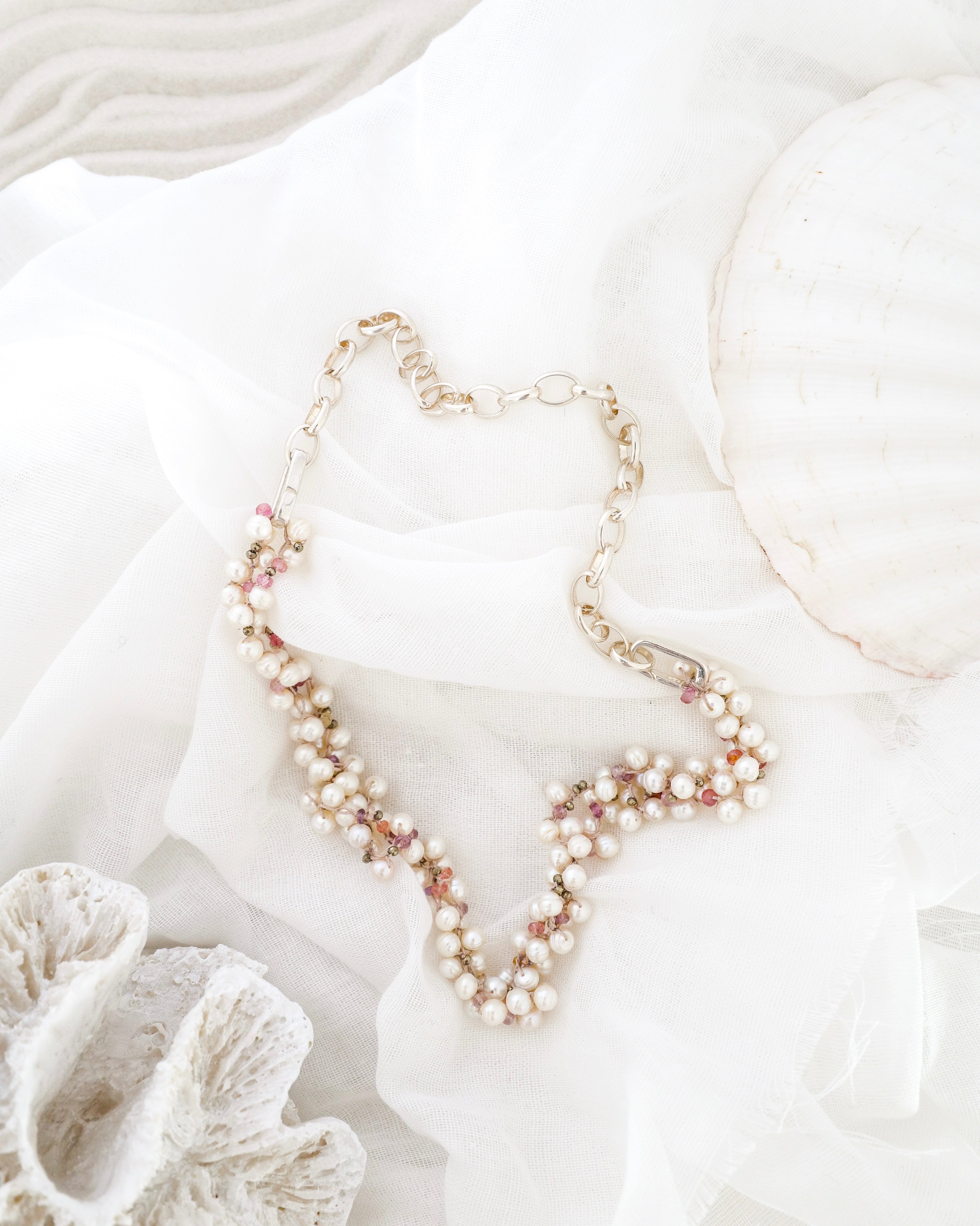 Pearl necklace on a white surface with shells