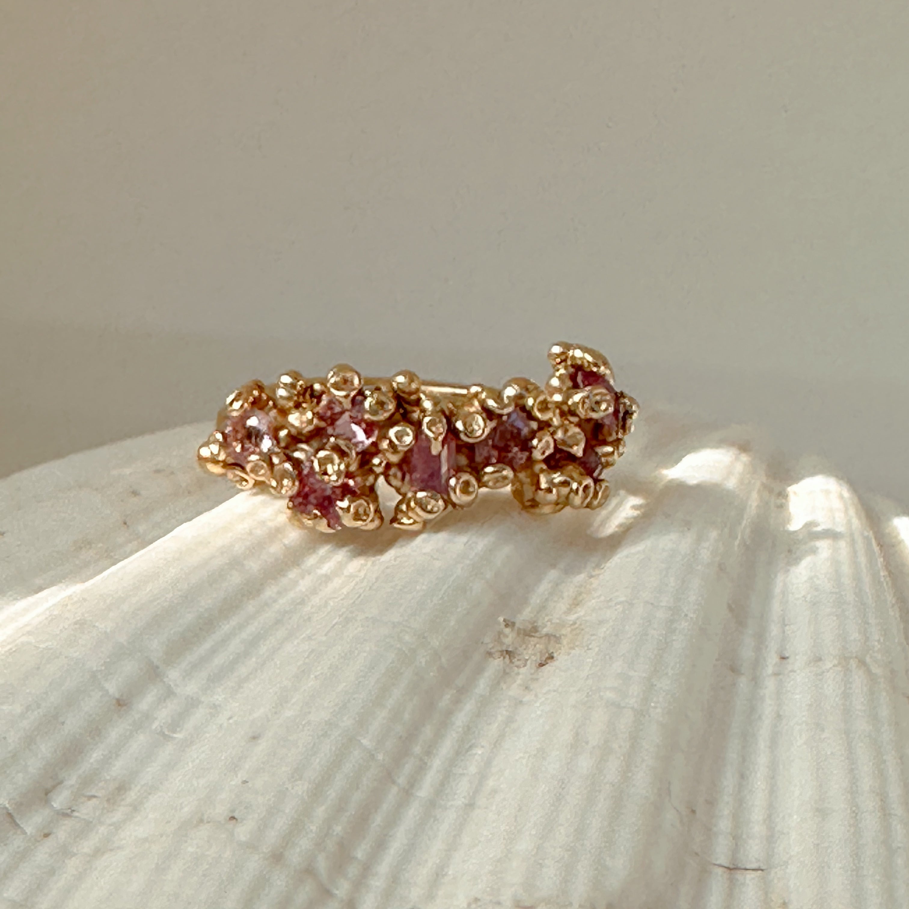 Gold ring with pink stones on a shell