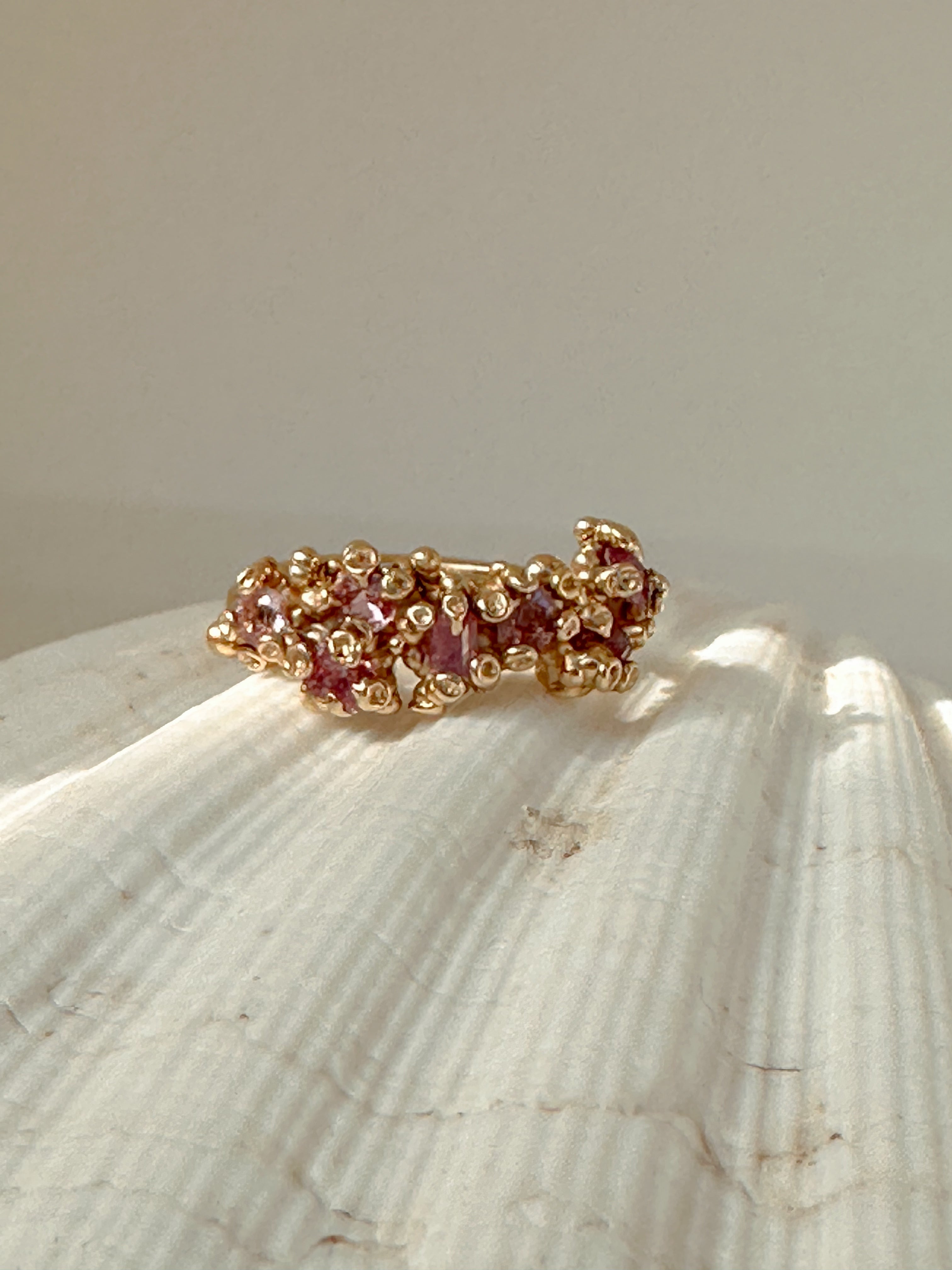 Gold ring with pink stones on a shell