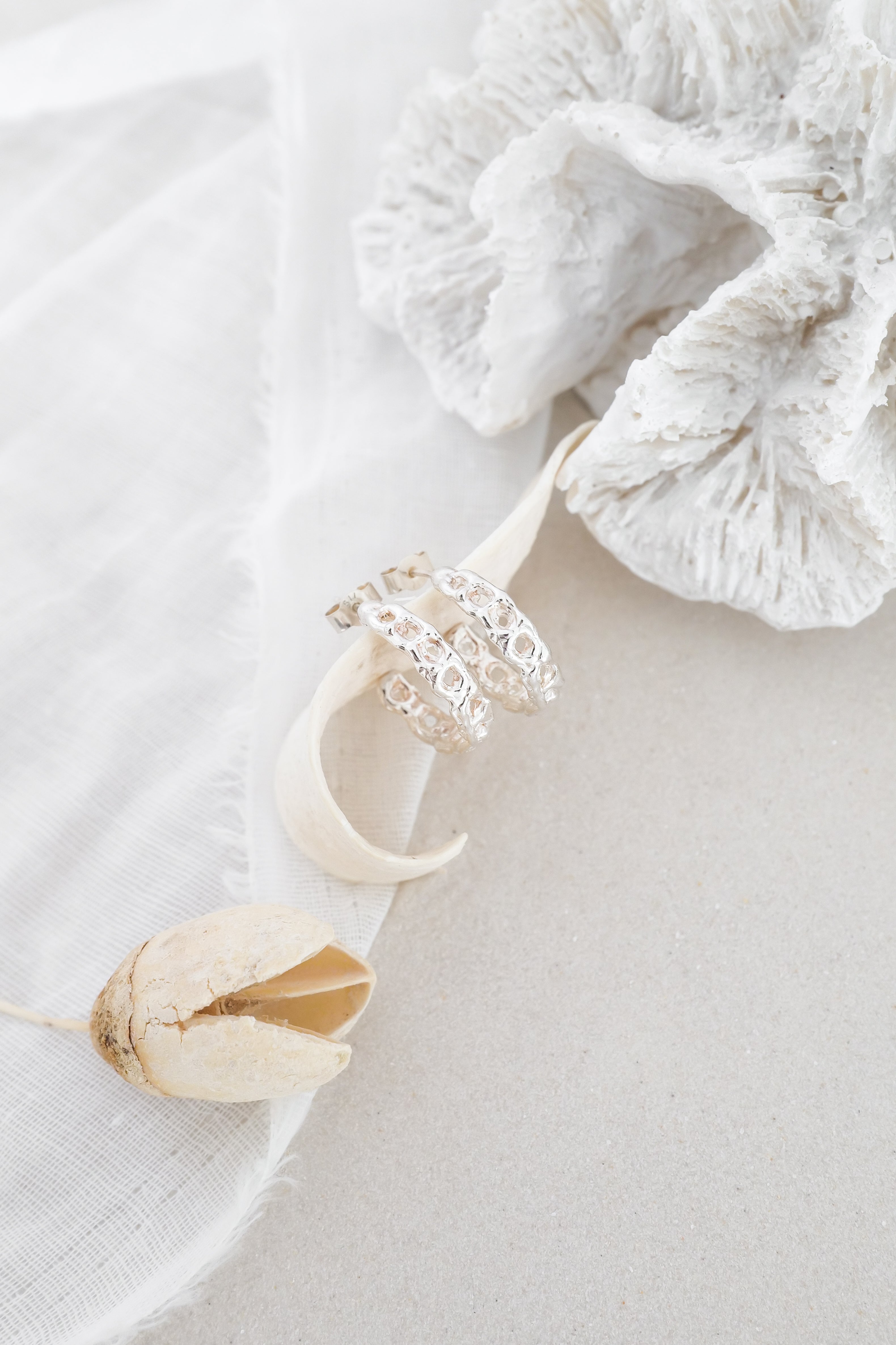 Silver hoops with white cloth and white coral in background