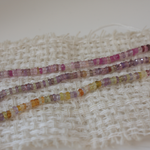 Colorful beaded strands on a textured fabric background