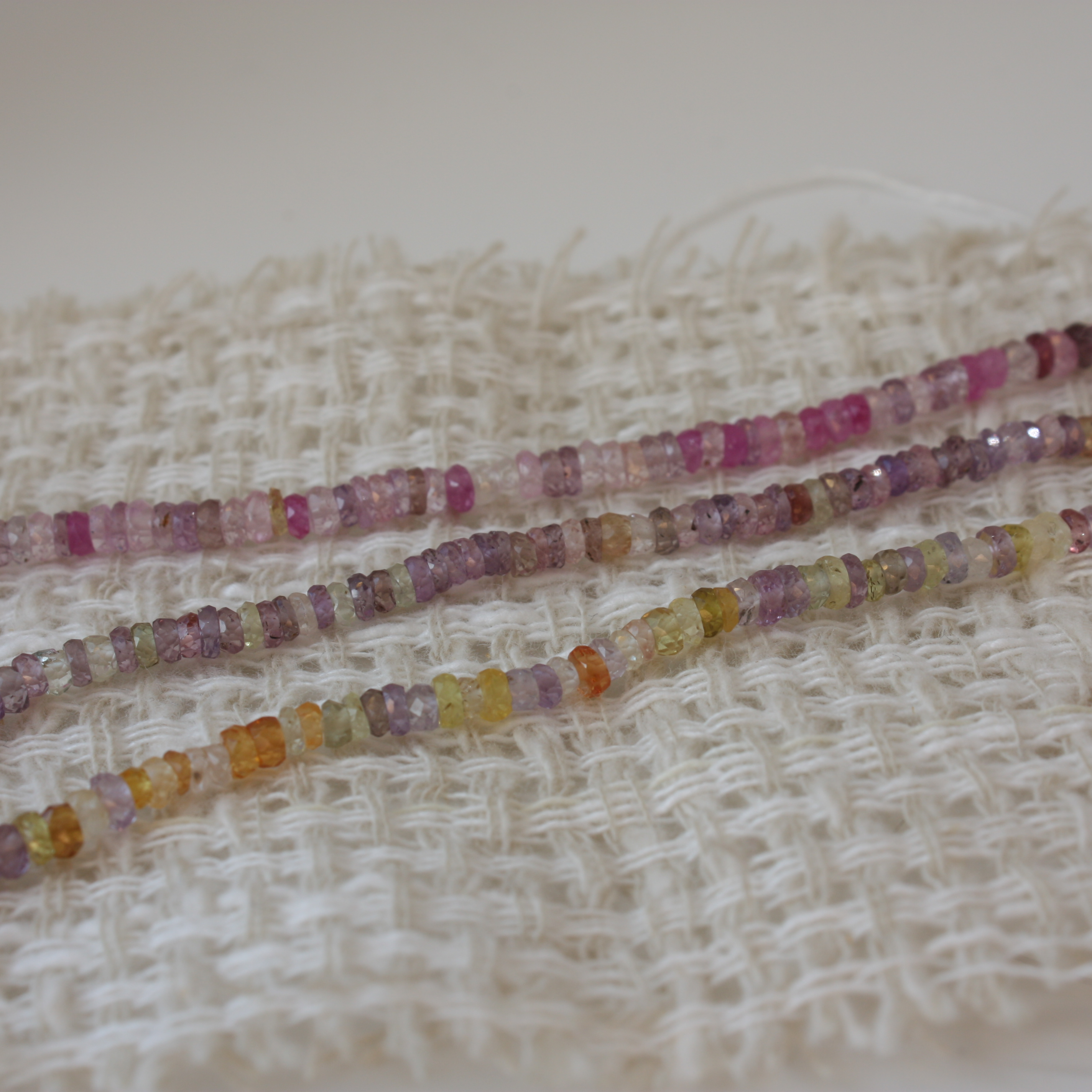 Colorful beaded strands on a textured fabric background