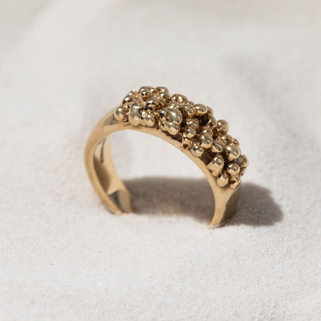 Gold granulated ring in sand