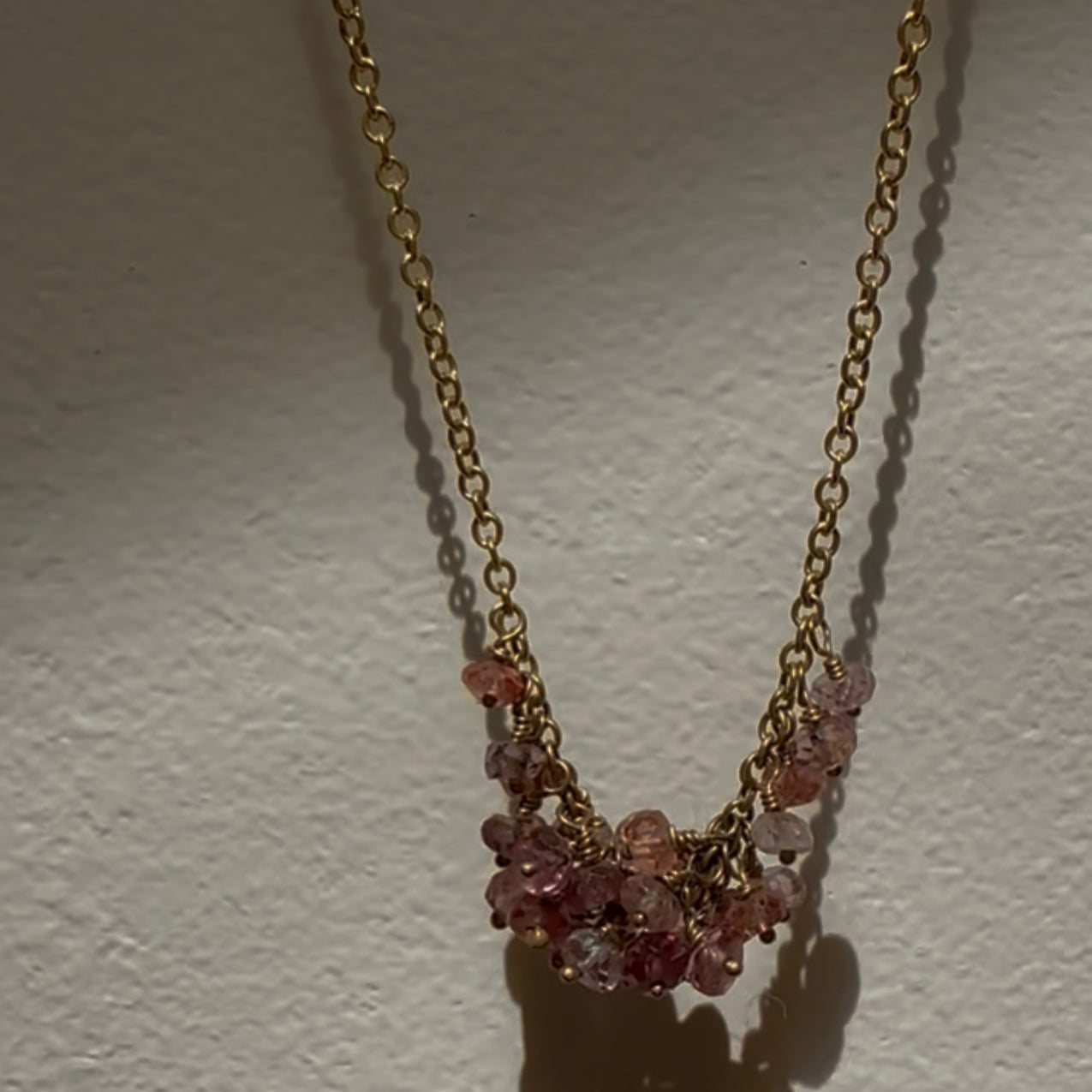 Necklace with pink gemstones on a gold chain against a white background