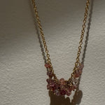 Necklace with pink gemstones on a gold chain against a white background