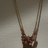 Necklace with pink gemstones on a gold chain against a white background
