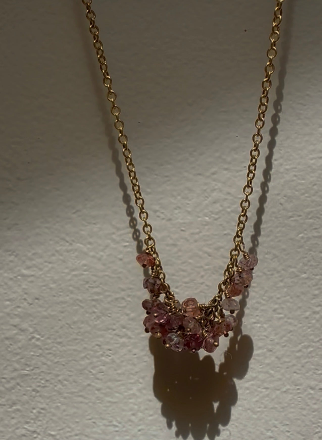 Necklace with pink gemstones on a gold chain against a white background
