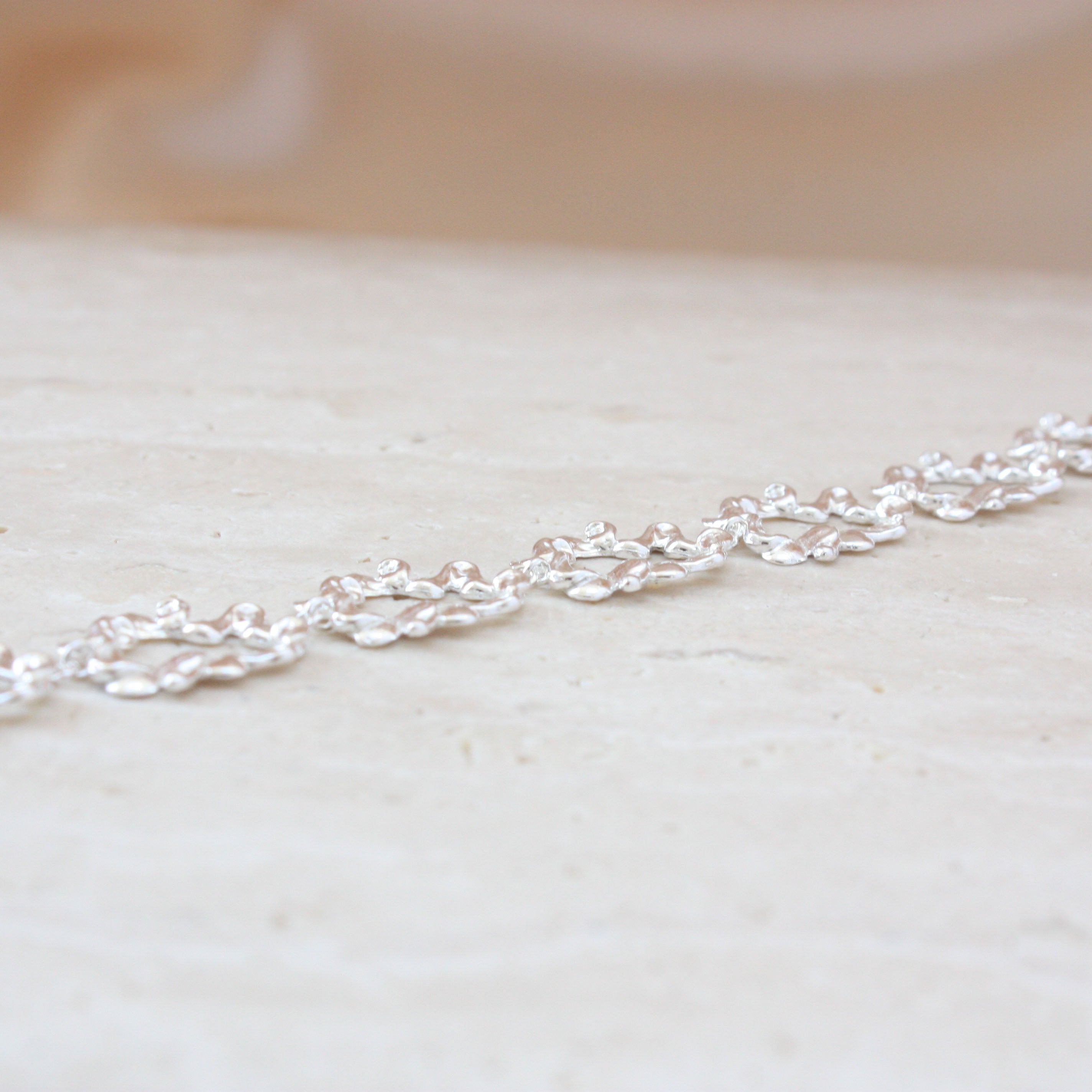 Textured link bracelet on stone and cream background