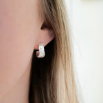 Close-up of a person wearing a silver hoop earring with a blurred background
